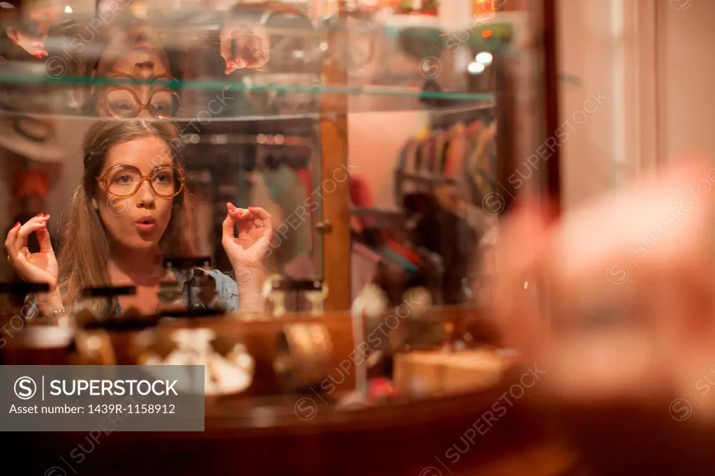 Young woman trying on glasses and pulling faces in vintage shop