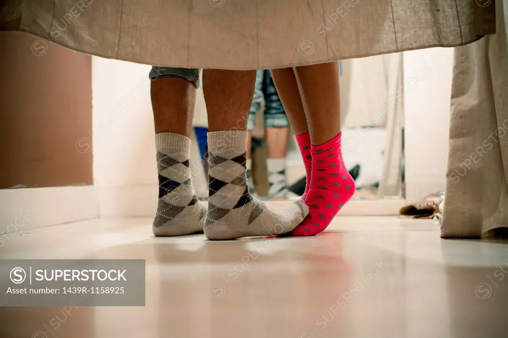 Young couple wearing socks in changing room, low section