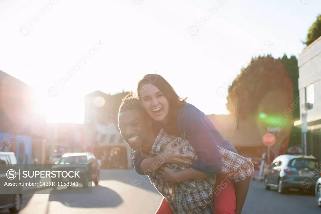 Young man giving woman piggy back