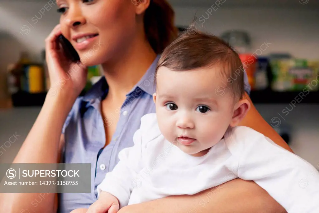 Mother holding baby girl whilst on the phone