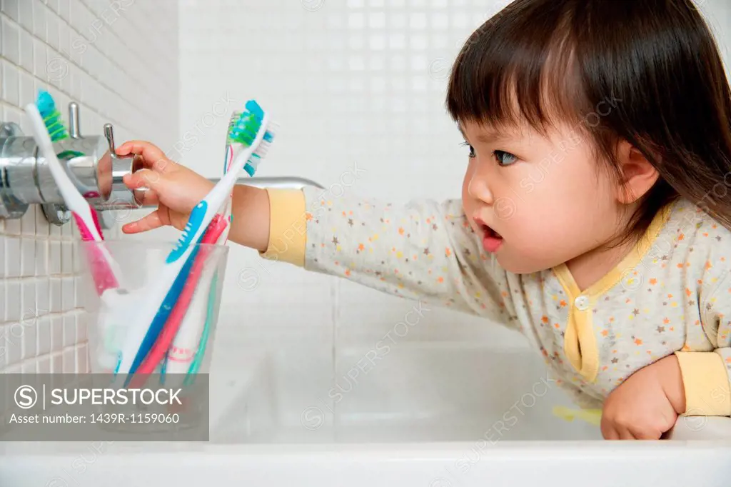 Close up of girl toddler turning bathroom sink taps