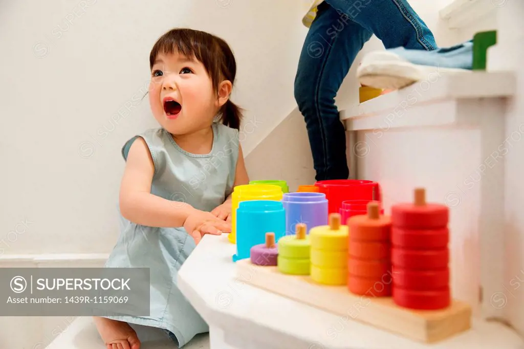Female toddler playing with toys on staircase