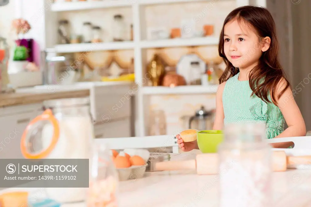 Young girl at kitchen counter measuring ingredients