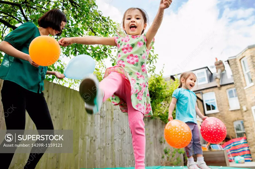 Mother and daughters playing in garden with balloons