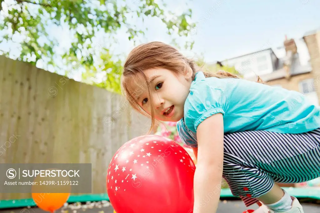 Young girl playing in garden with balloons