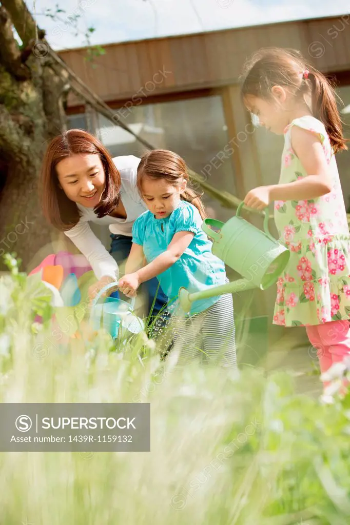 Mother and daughters watering garden