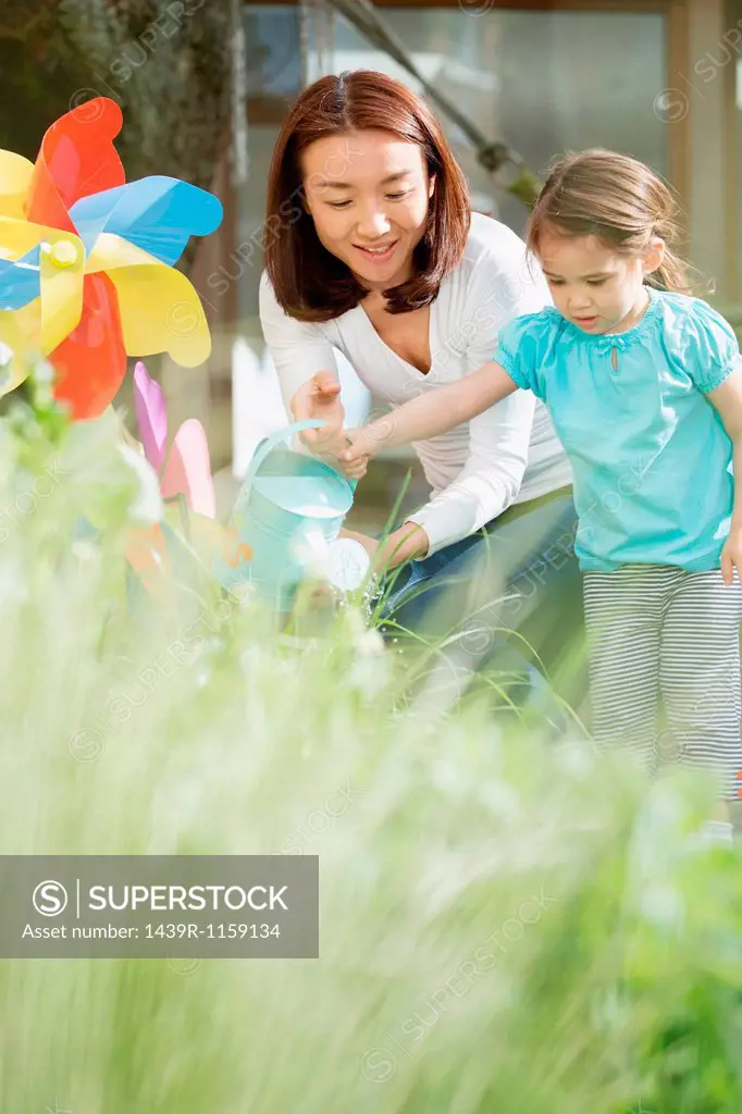 Mother and young daughter with watering can and toy windmill