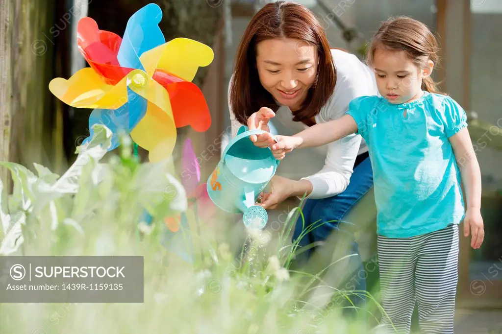 Mother and daughter with watering can and toy windmill