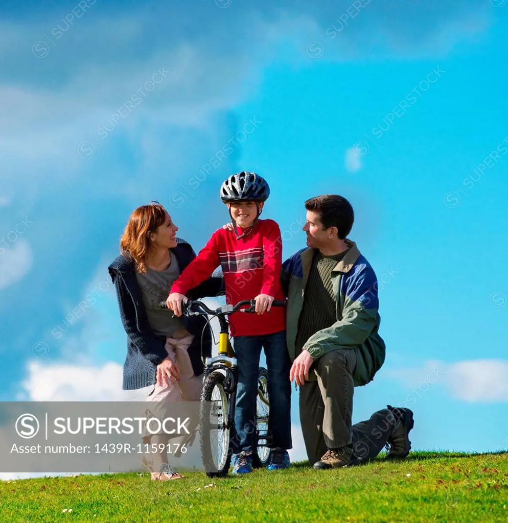 Mother and father encouraging son to ride bicycle