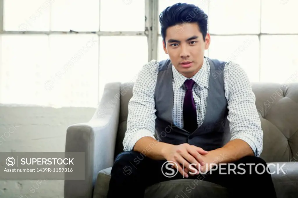 Portrait of young businessman sitting on office sofa