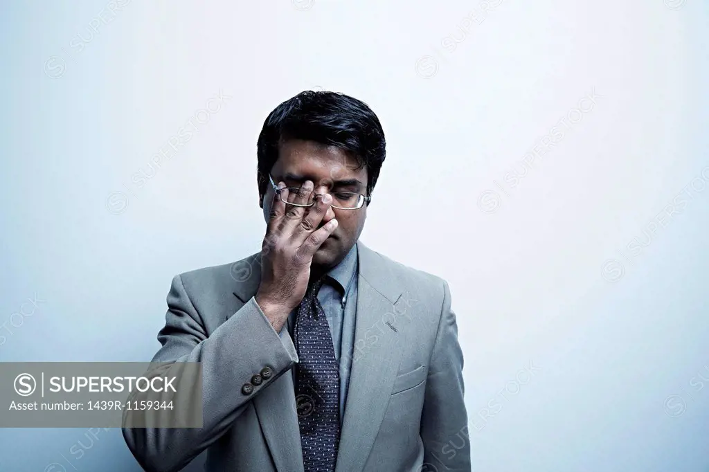 Studio portrait of businessman rubbing his eye