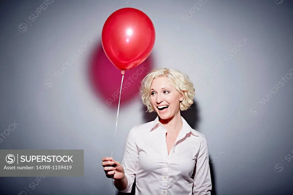 Studio portrait of mature woman with red balloon
