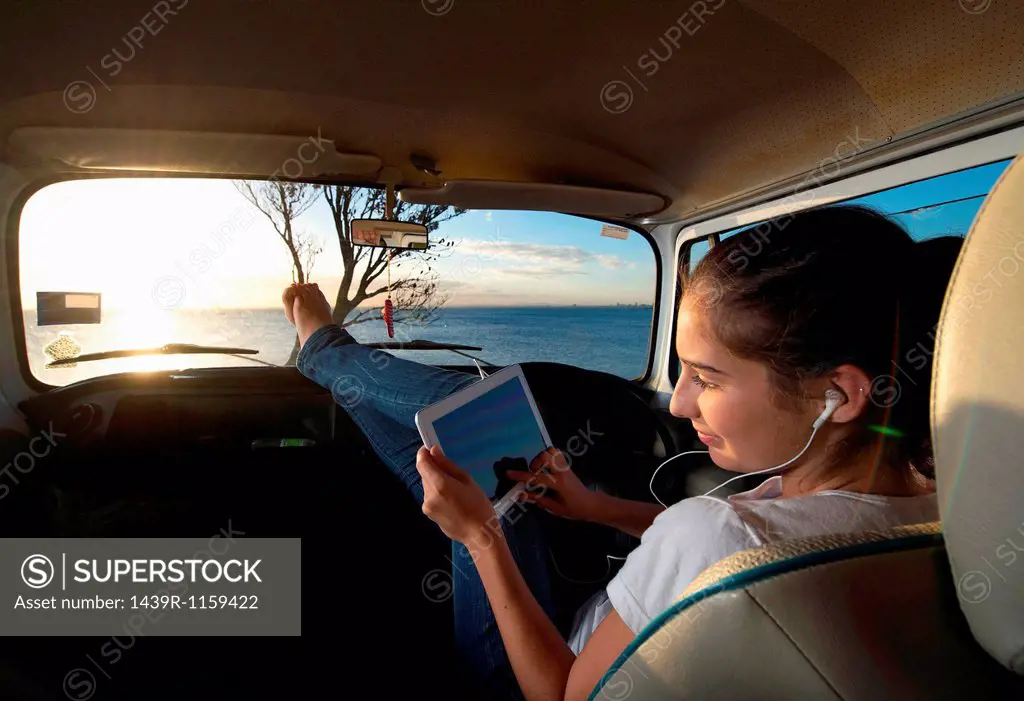 Young woman in camper van using digital tablet