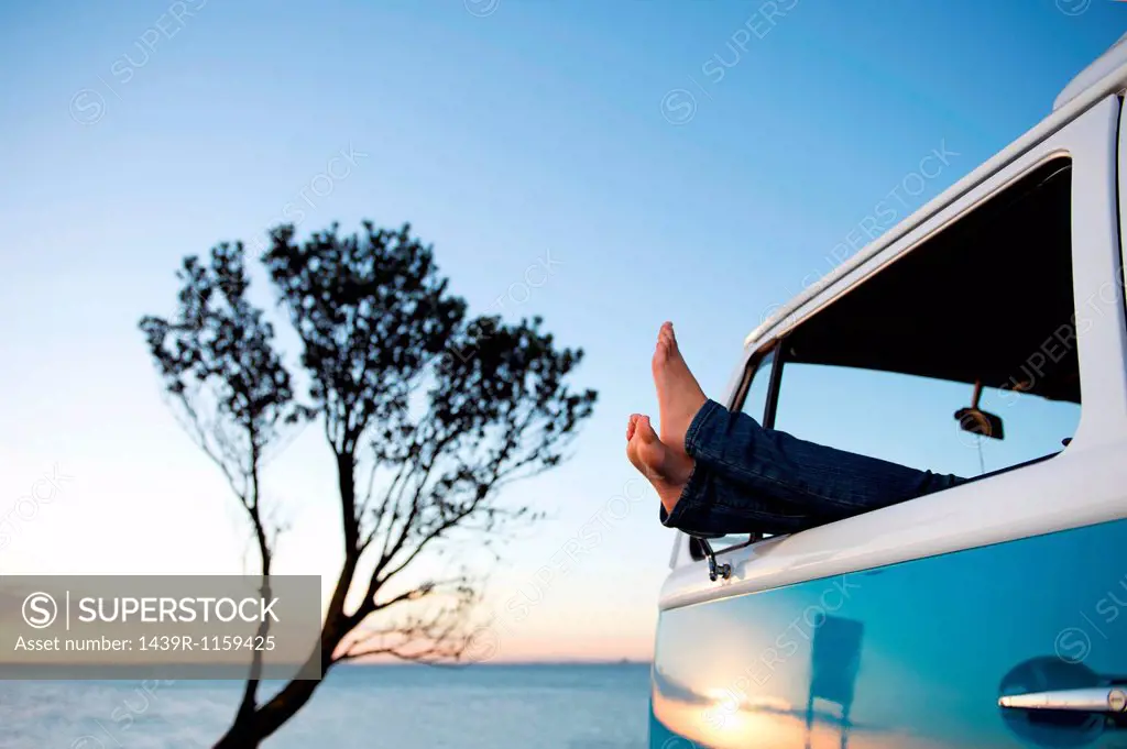 Feet out of camper van window at dusk