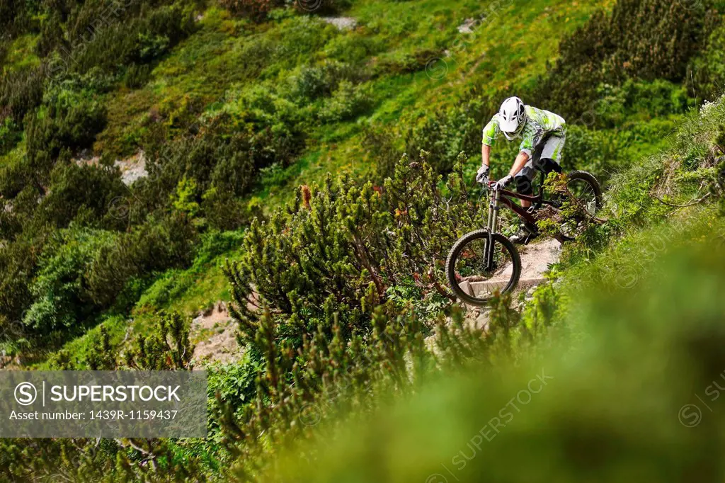 Mountain biker riding down steep hill path