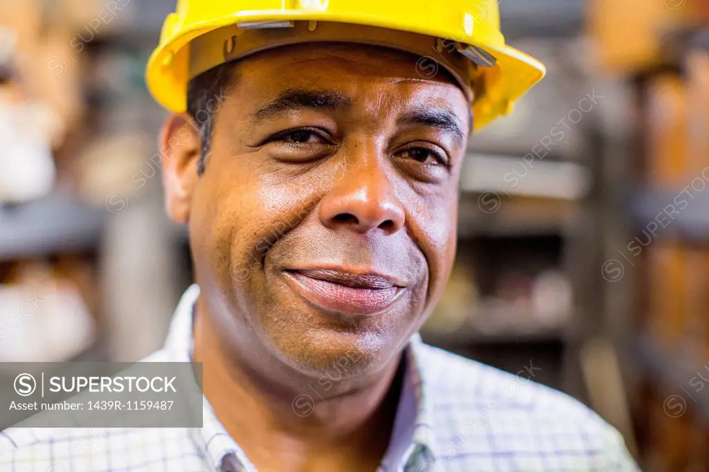 Close up portrait of man in stockroom wearing hard hat