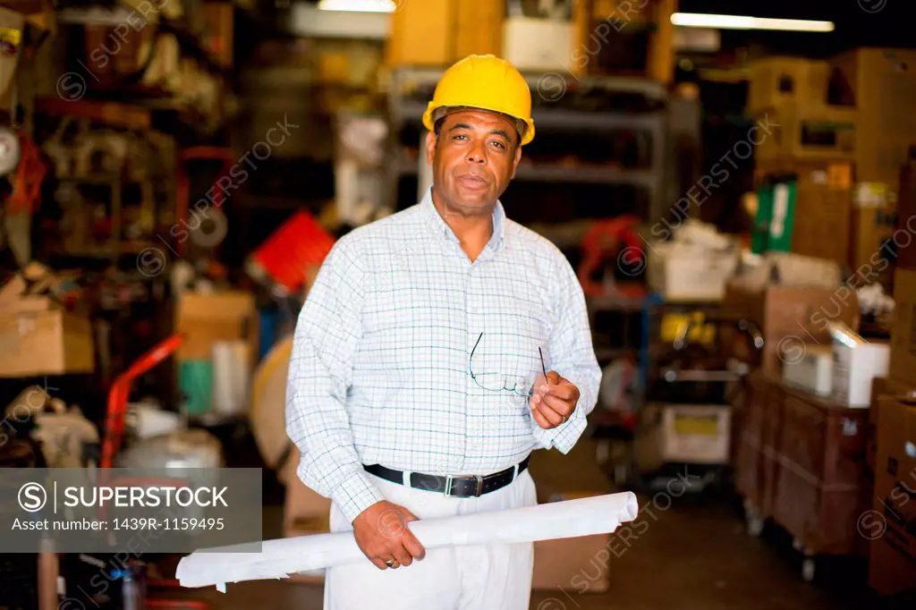 Portrait of man in warehouse holding blueprint