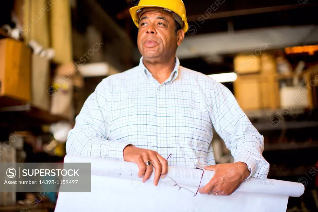 Man in warehouse rolling up blueprint