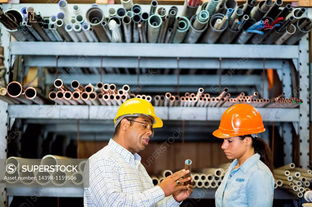 Two warehouse workers looking at copper pipe