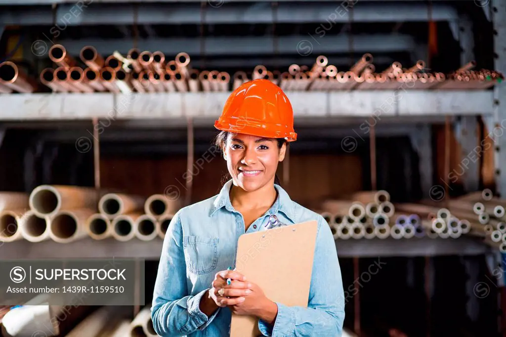 Portrait of woman in warehouse with clipboard