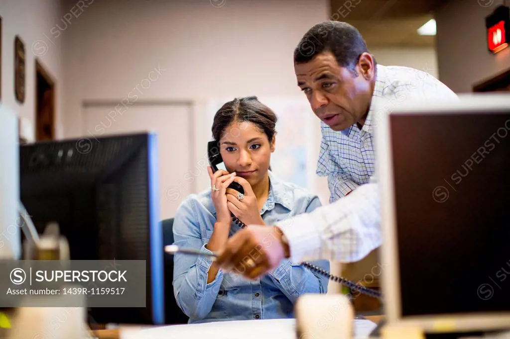 Colleagues in office looking at computer screen