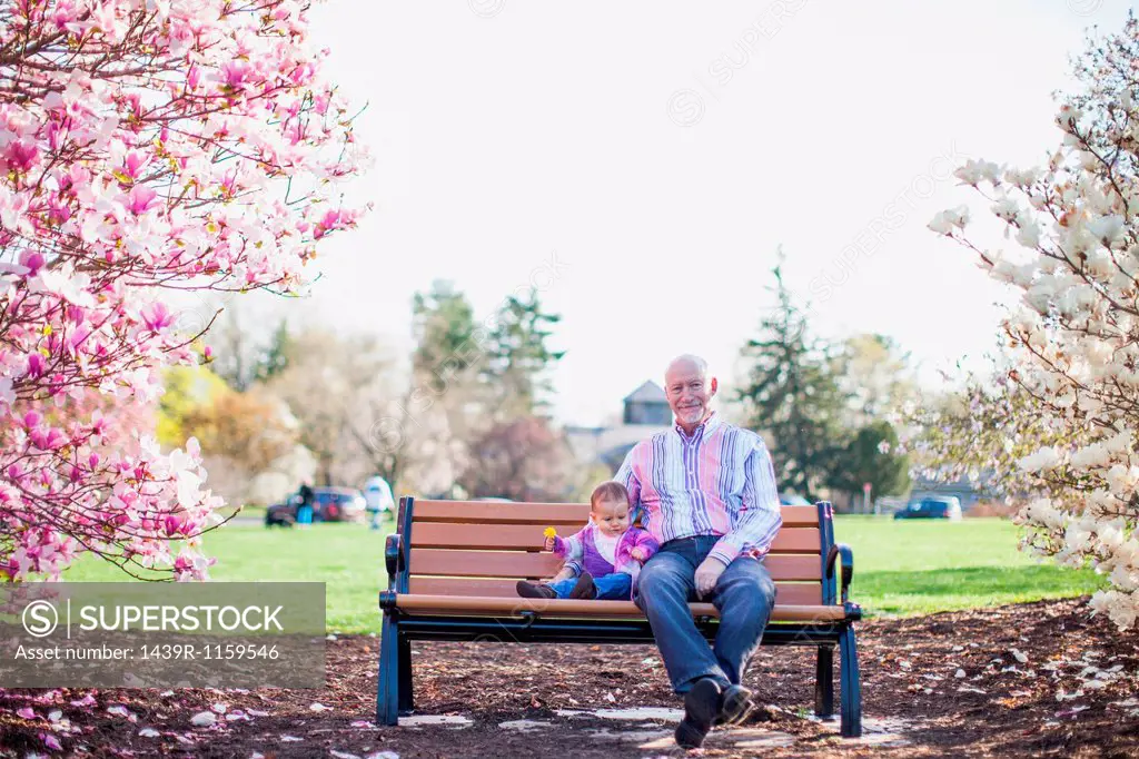 Grandfather and granddaughter sitting on park bench