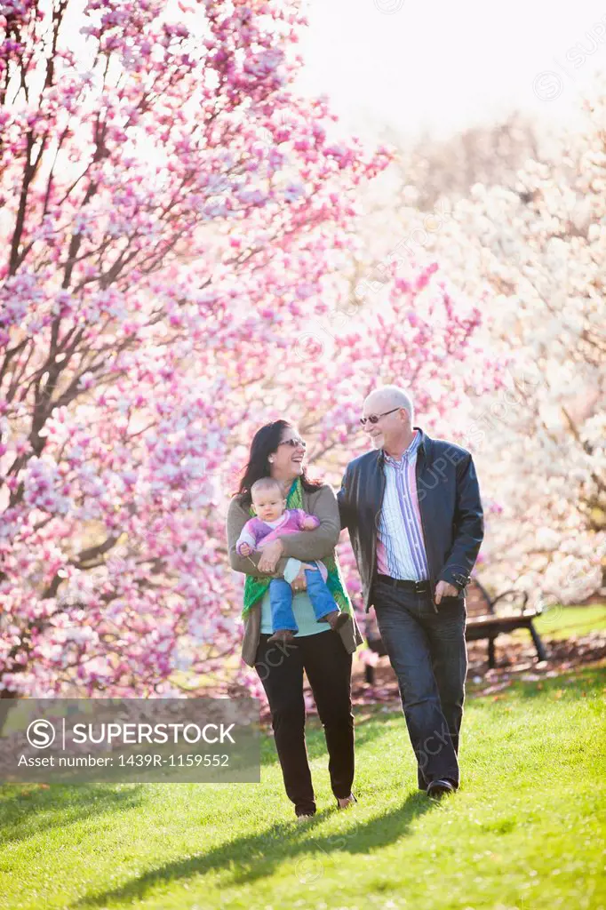 Grandparents and granddaughter walking in park