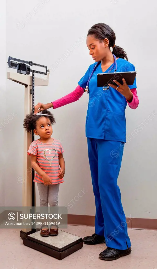 Nurse measuring height of young patient