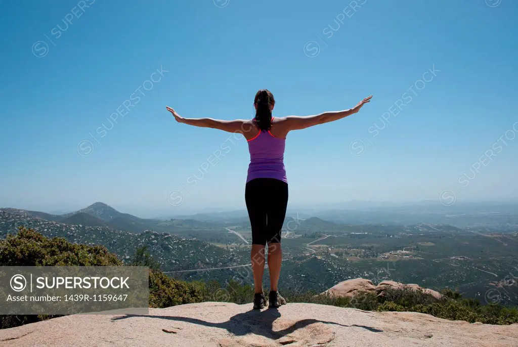 Woman with outstretched arms overlooking view of San Diego, California, USA