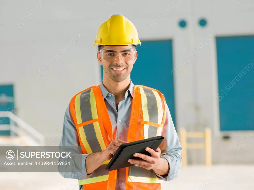 Mid adult construction worker using digital tablet, portrait