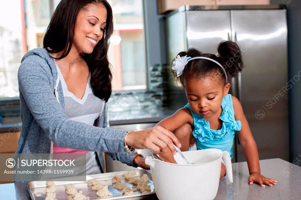 Mid adult woman baking with daughter in kitchen