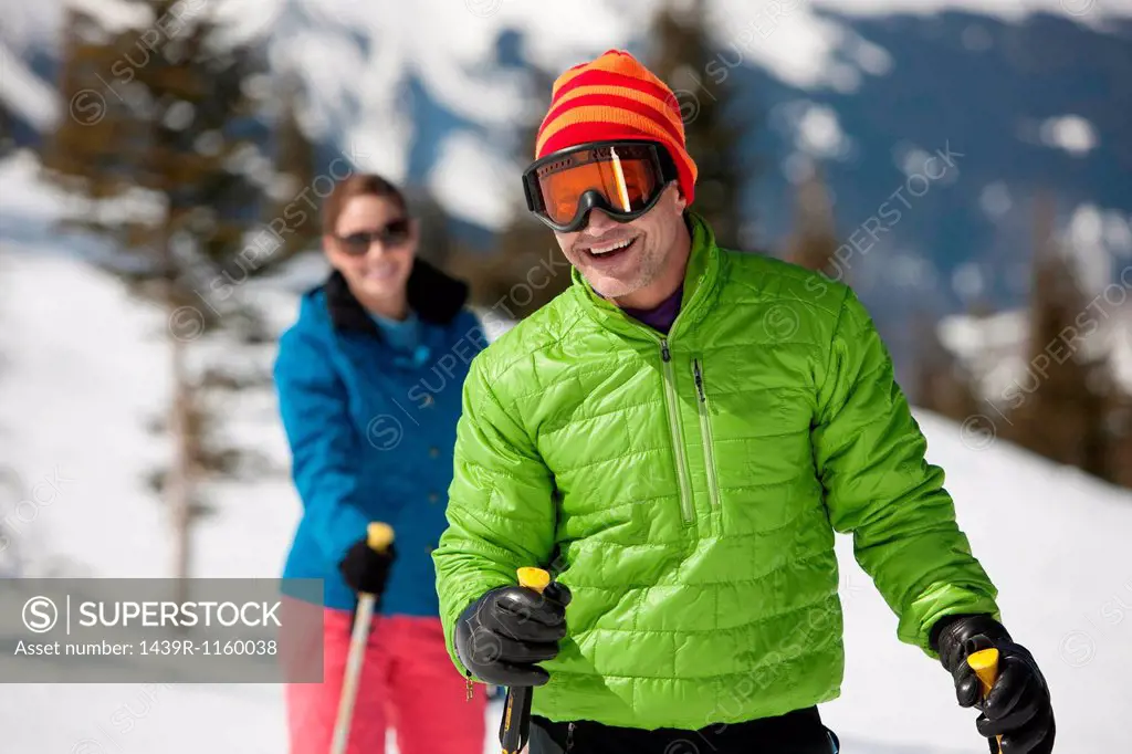 Mature man in skiwear holding ski poles, portrait