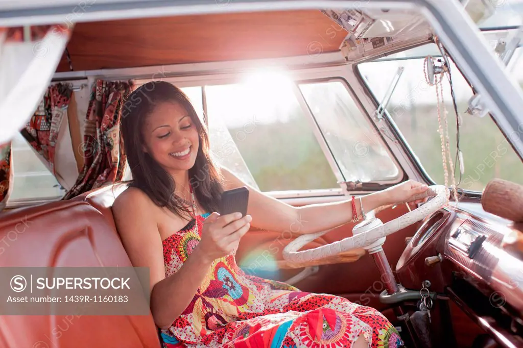 Young woman using mobile phone in camper van