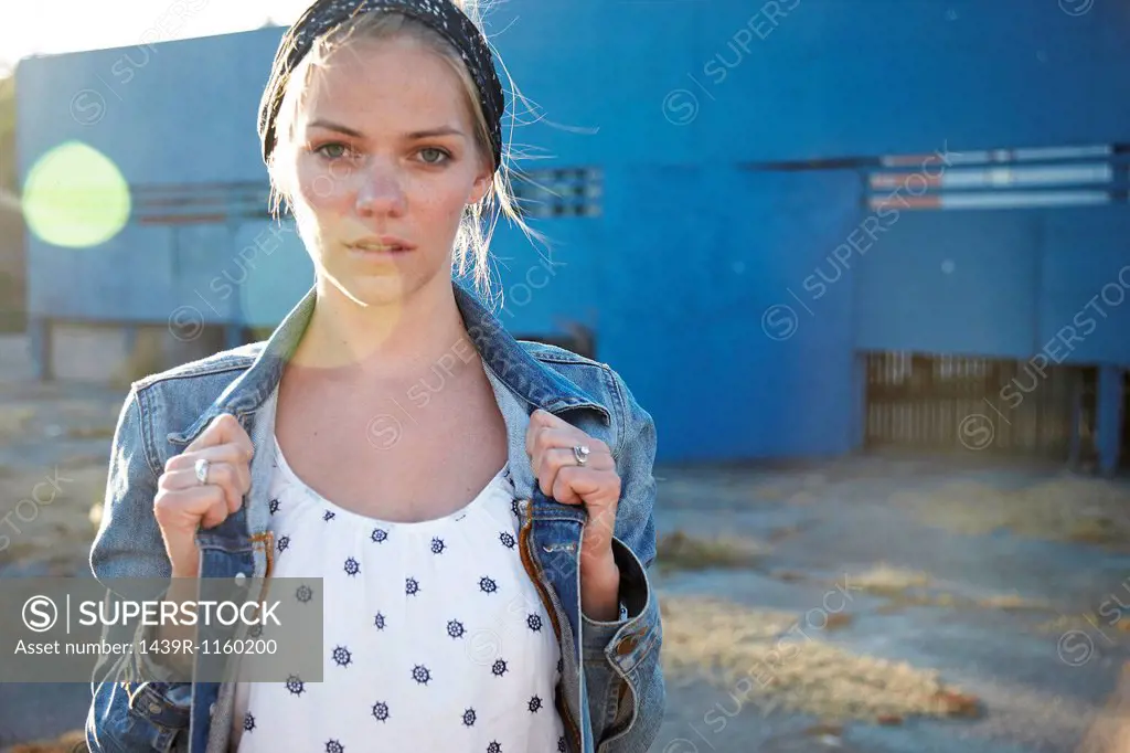 Portrait of woman holding jacket collar in industrial district