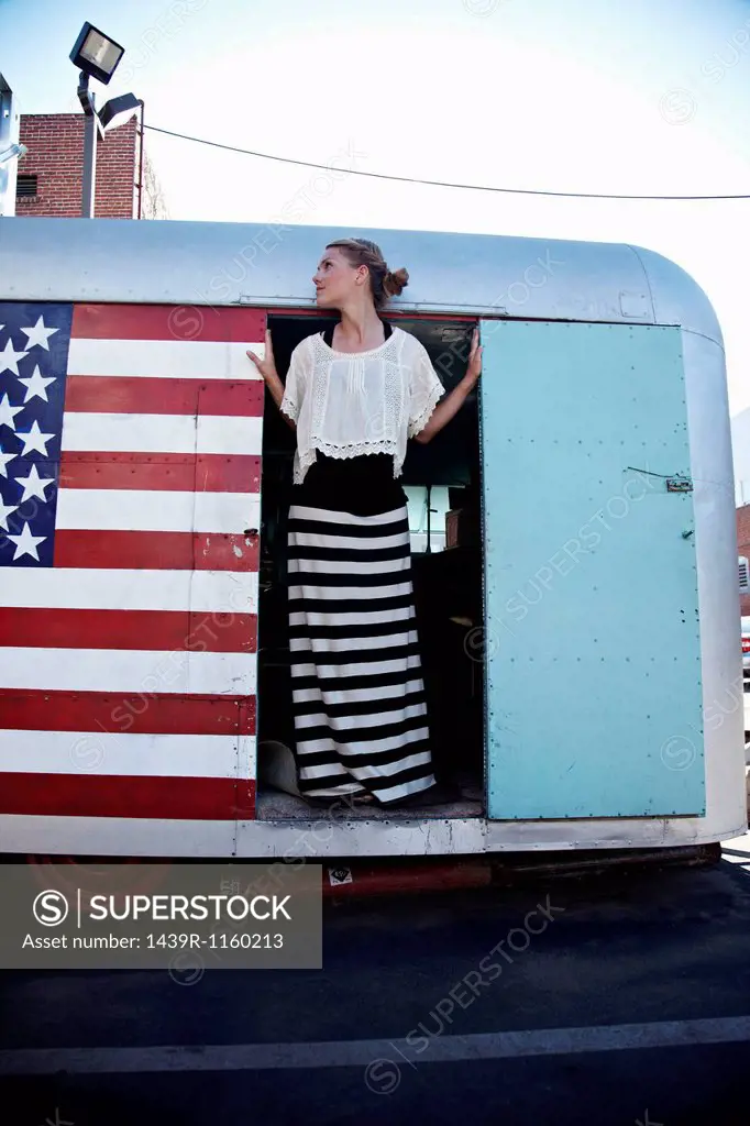 Woman standing in doorway of caravan with American flag