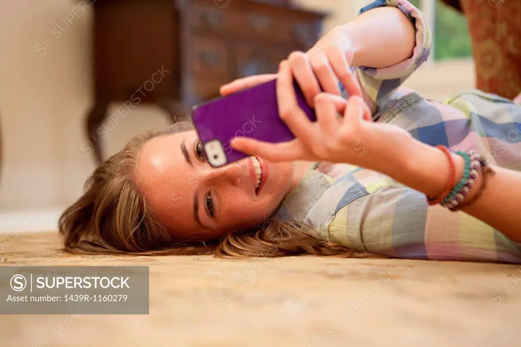 Teenage girl lying on floor with cell phone