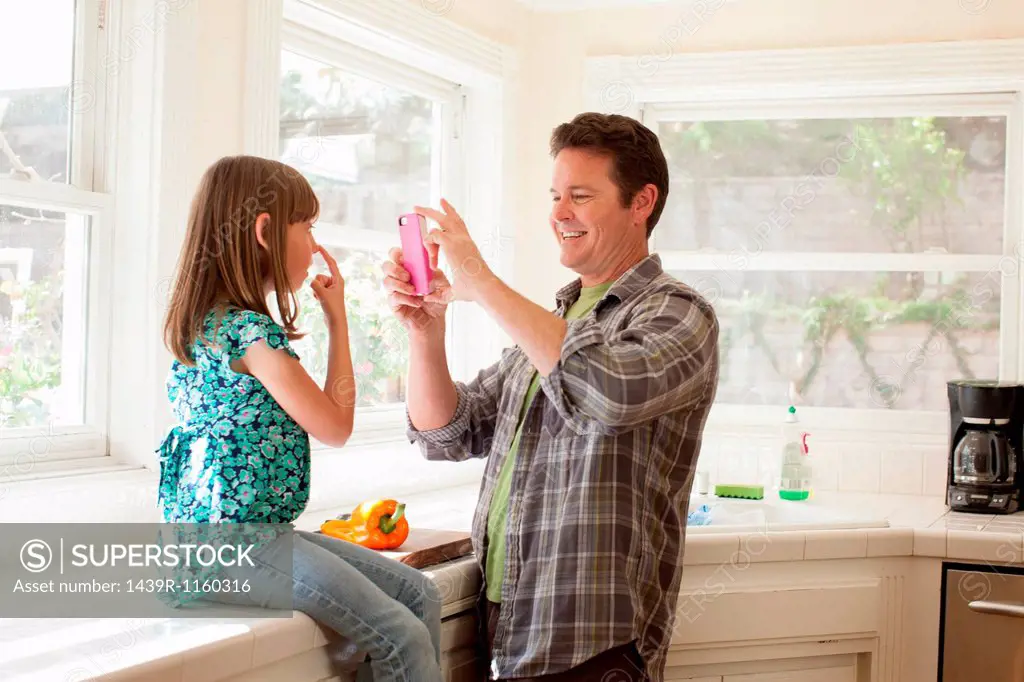 Father photographing daughter on smartphone