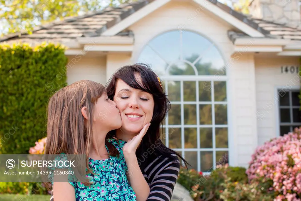 Portrait of daughter kissing mother on cheek in garden
