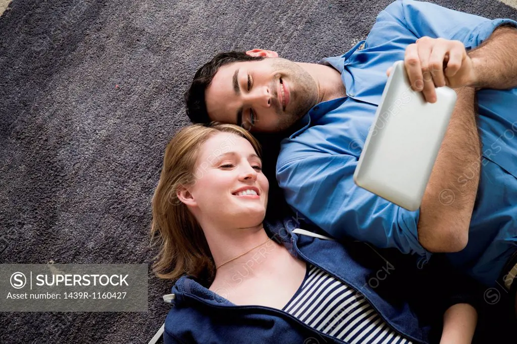 Young couple lying on floor with electronic book
