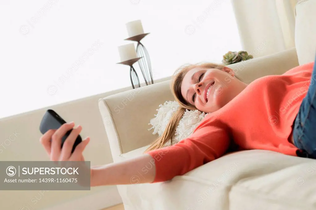 Teenage girl on sofa with cell phone, smiling
