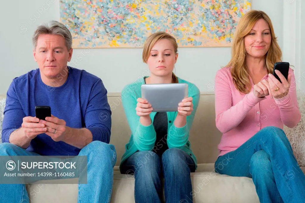 Family with teenage girl using communication devices
