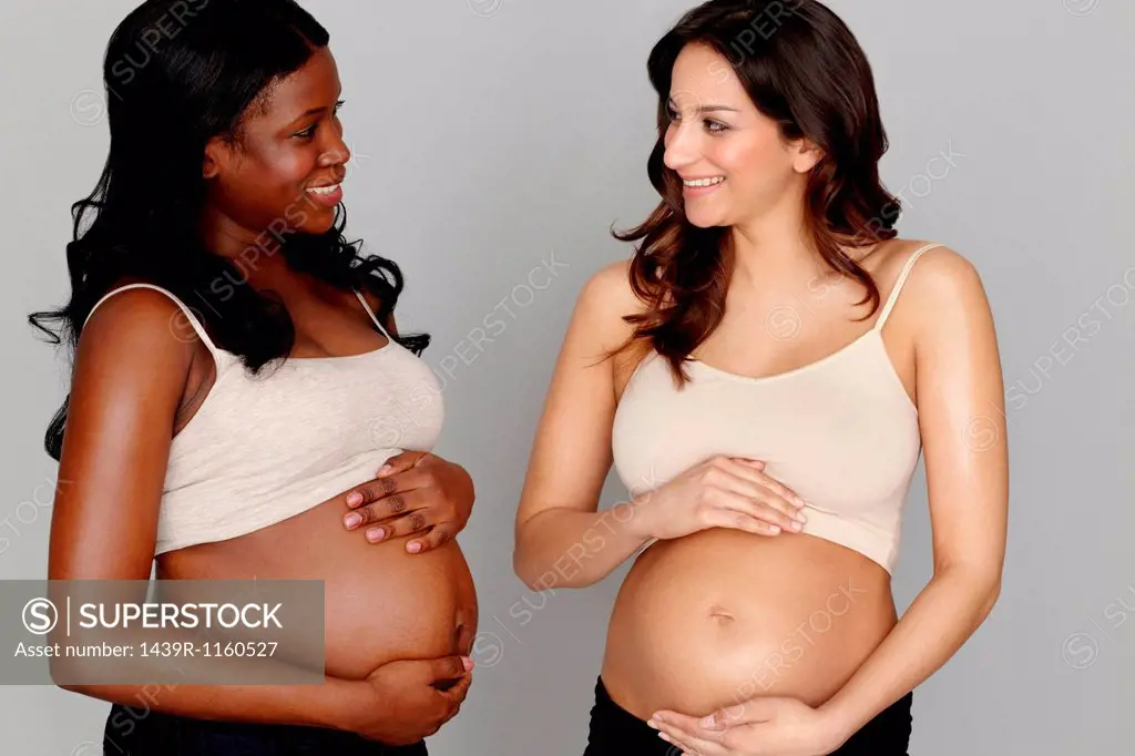 Two pregnant women touching stomachs