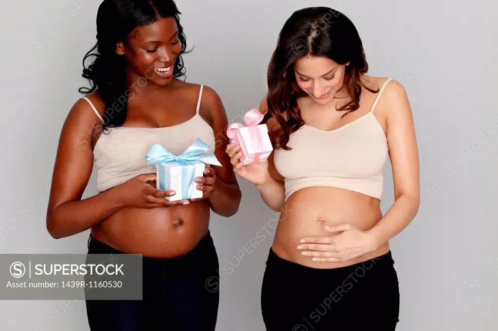 Two pregnant women with pink and blue gift boxes