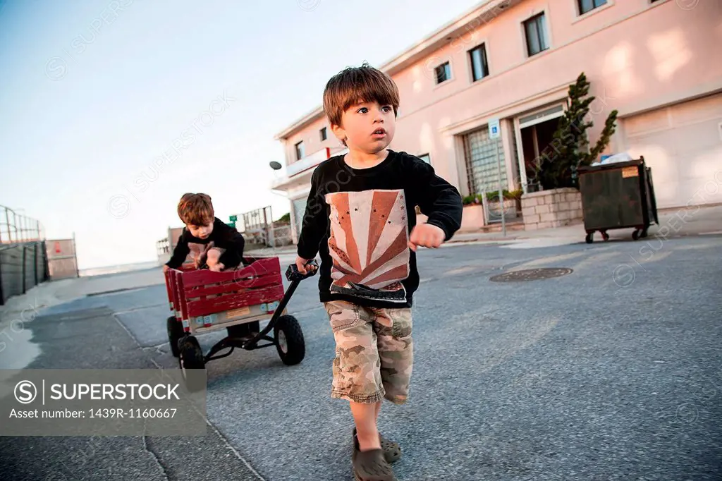 Boy pulling brother along in cart