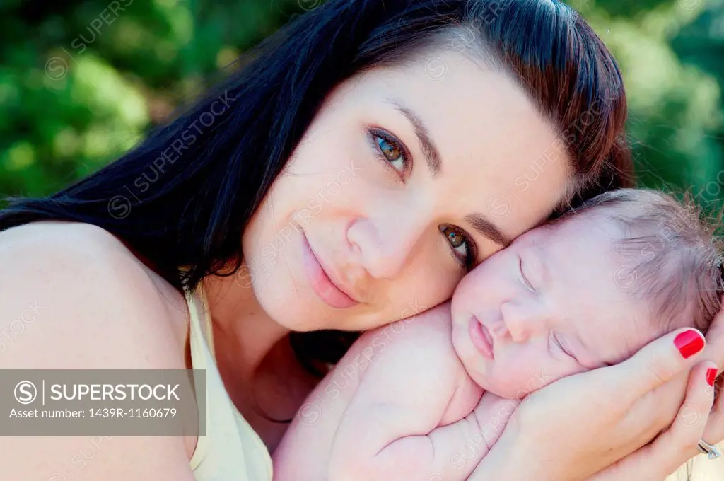 Portrait of mother holding newborn baby daughter