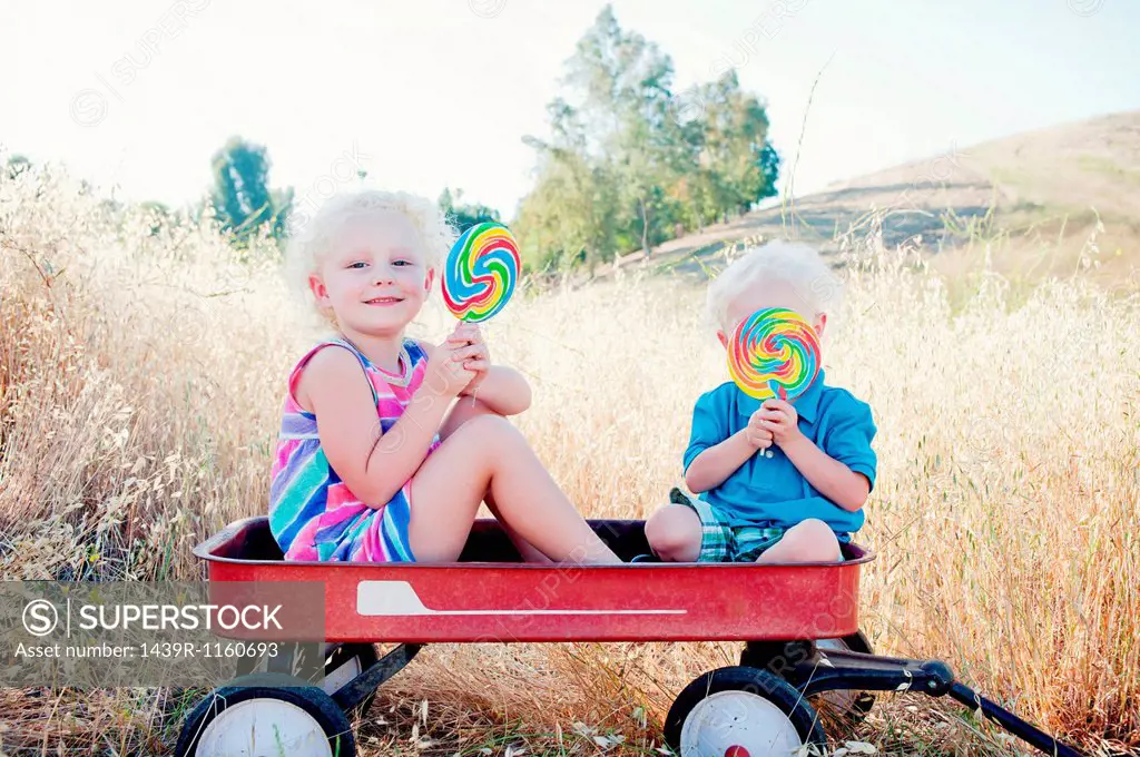 Brother and sister sitting in cart with lollipops