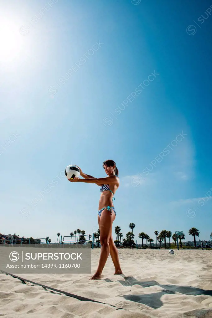 Mature woman serving in beach volleyball