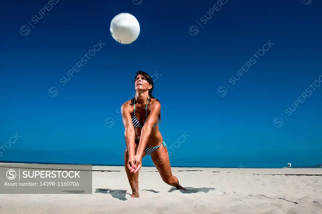Female beach volleyball player digging ball