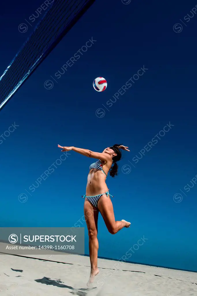 Female beach volleyball player hitting ball