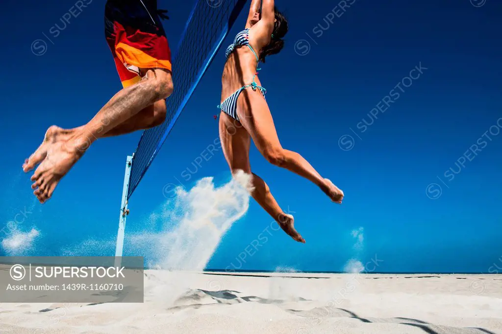 Two beach volleyball players blocking at net